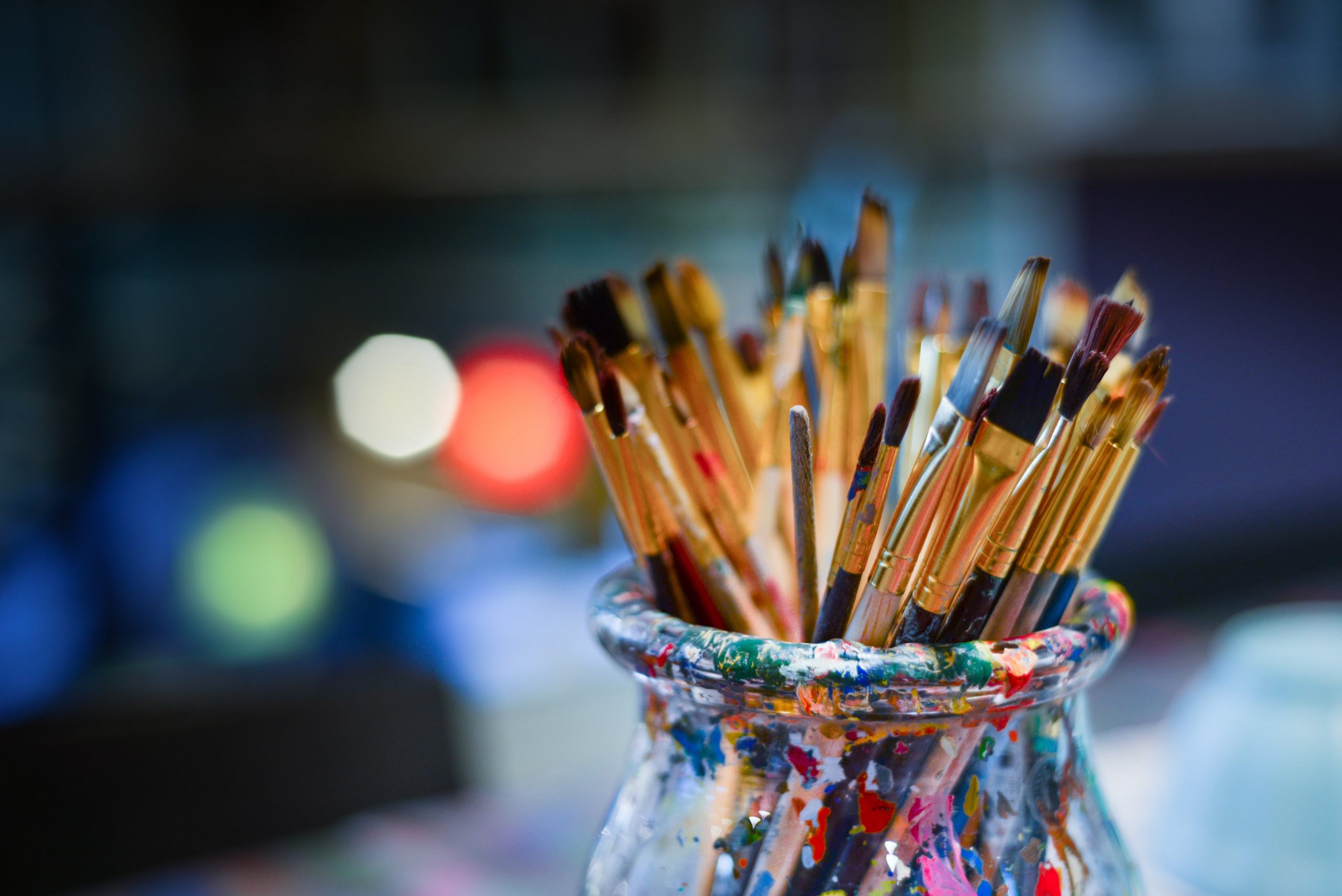 Paint splattered pot of paint brushes