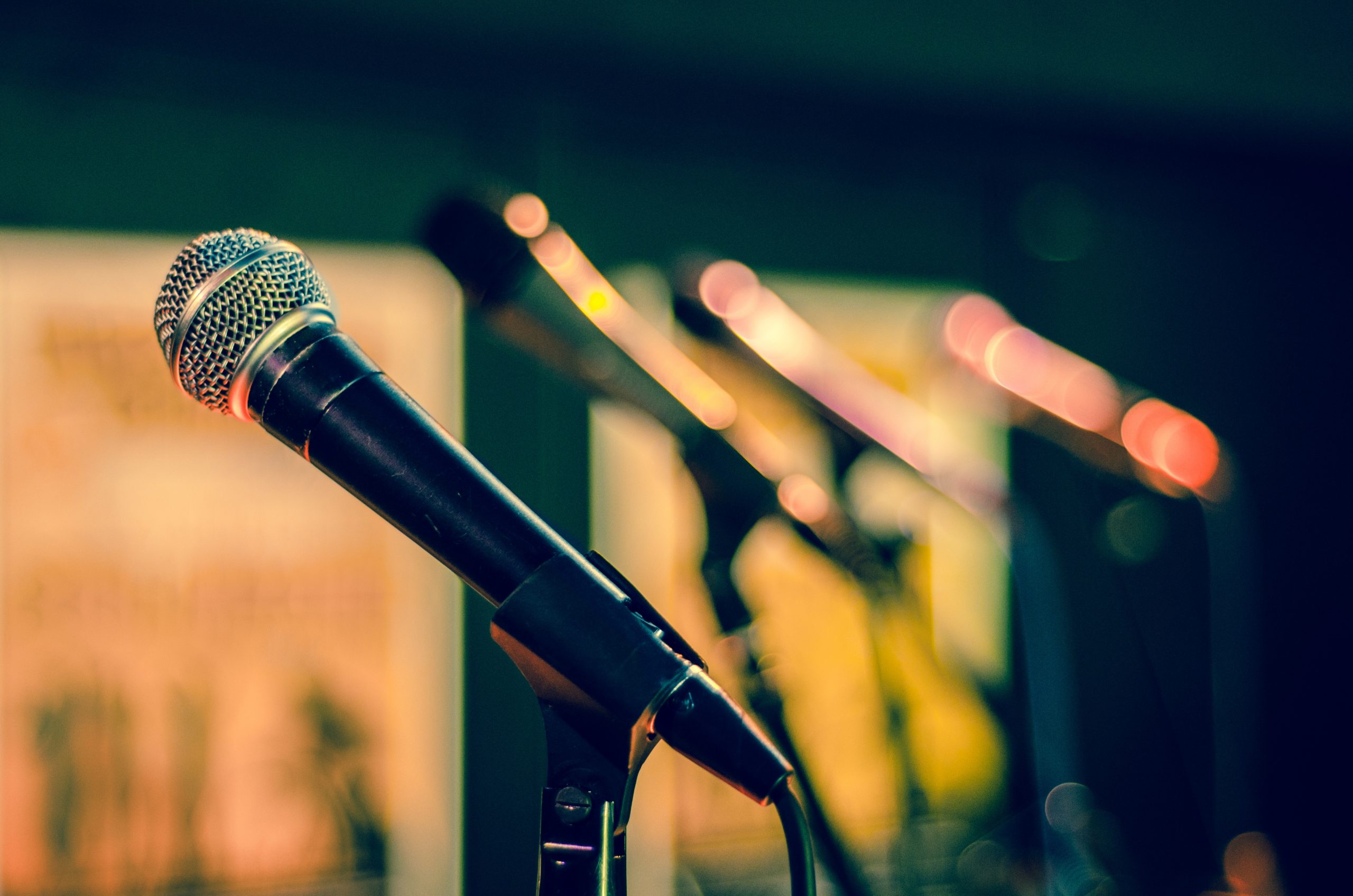 A line of microphones in microphone stands.