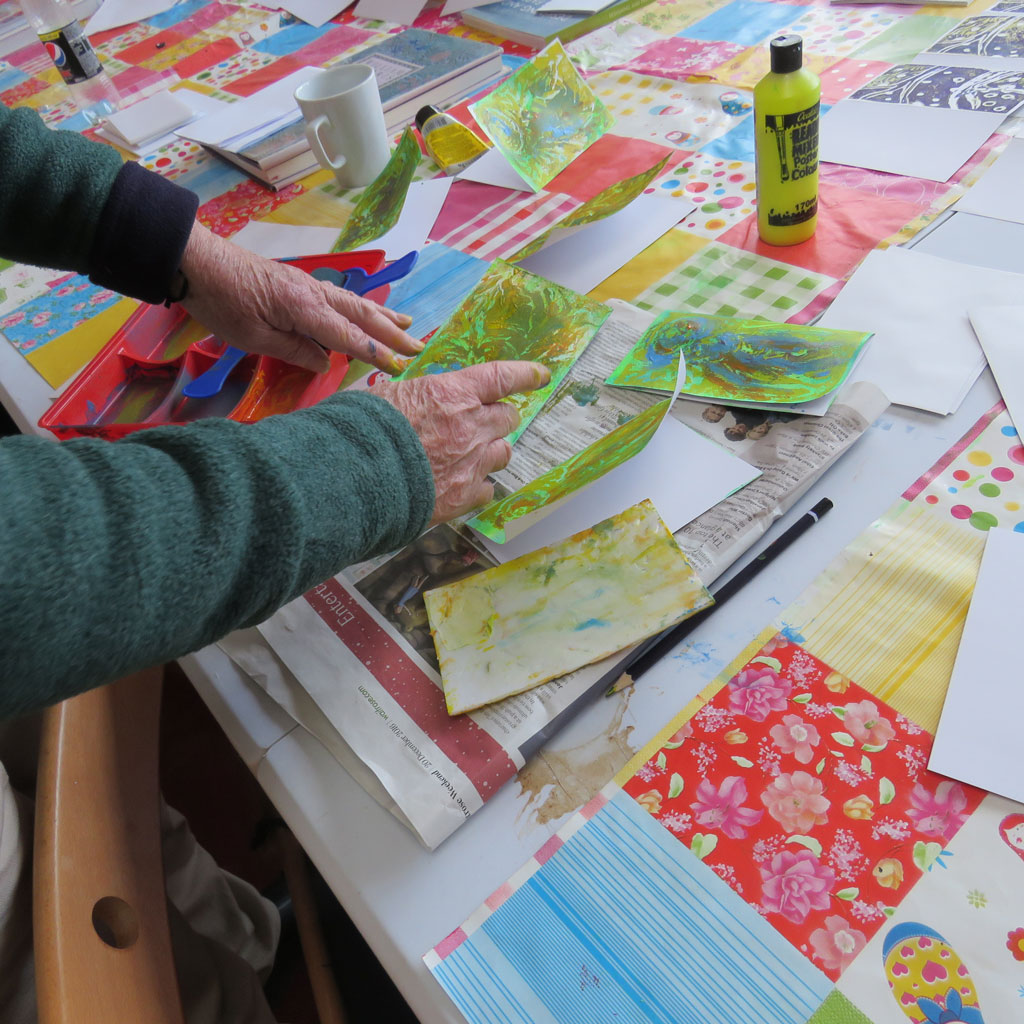 Close up of two hands with brightly coloured art work.