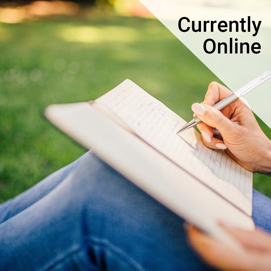 Close up of a woman sitting on grass writing in a notebook with the wording 'Currently online'.