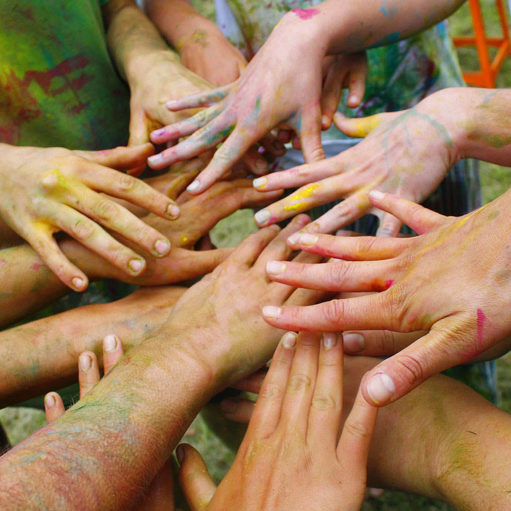 Multiple pairs of paint marked splayed hands gathered together.