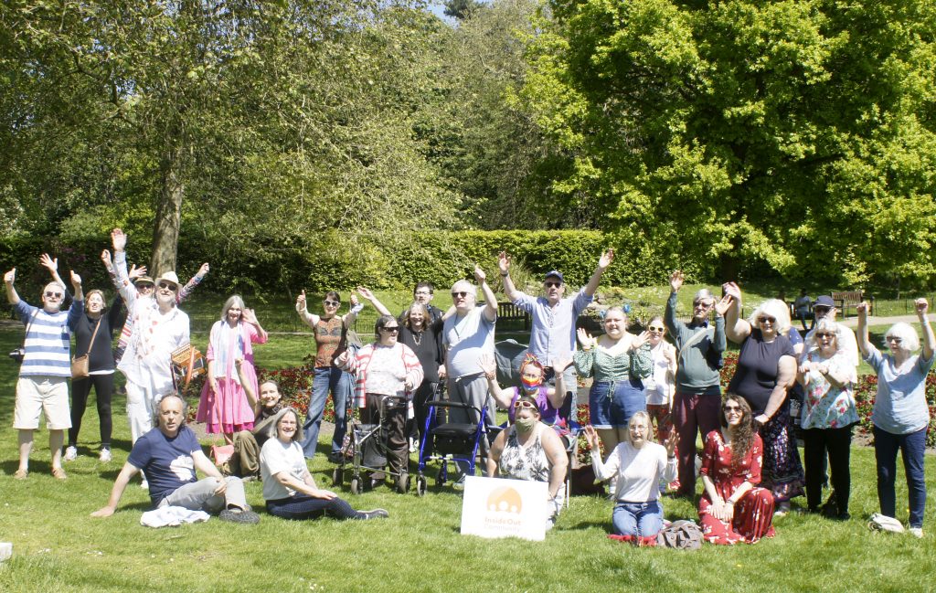 A group of adults gathered in a park cheering.