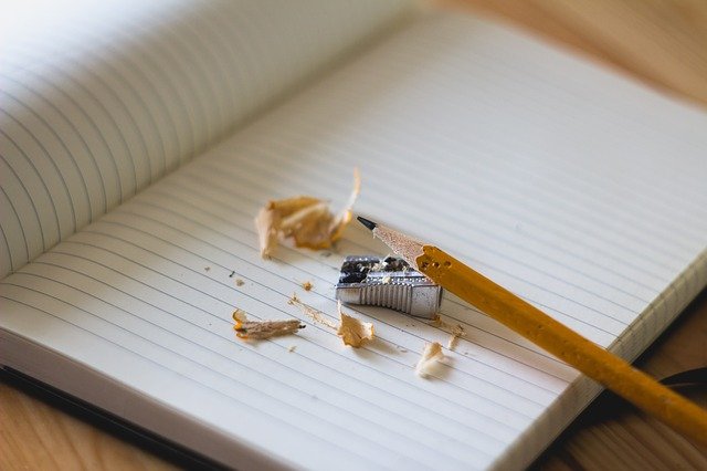 Blank lined note pad with a pencil, sharpener and pencil sharpenings.