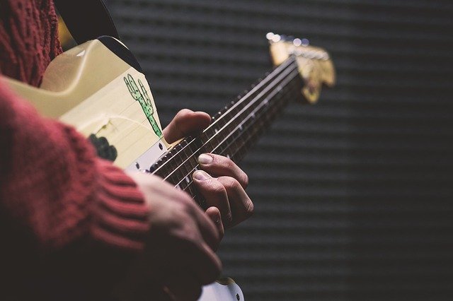 Close up images of a person holding a guitar with fingers on the strings.